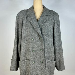 May include: A gray and white herringbone pattern double-breasted coat with two front pockets and four green buttons. The coat is displayed on a mannequin.