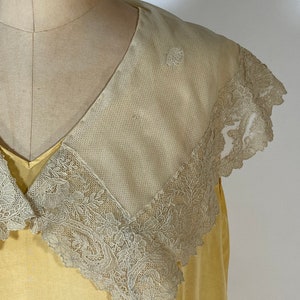 May include: A yellow vintage dress with a large, white lace collar. The collar is trimmed with delicate floral lace.