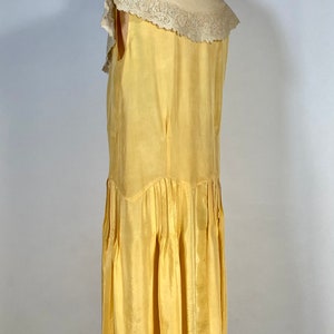 May include: A sleeveless yellow silk dress with a white lace collar. The dress has a pleated skirt and a fitted bodice.
