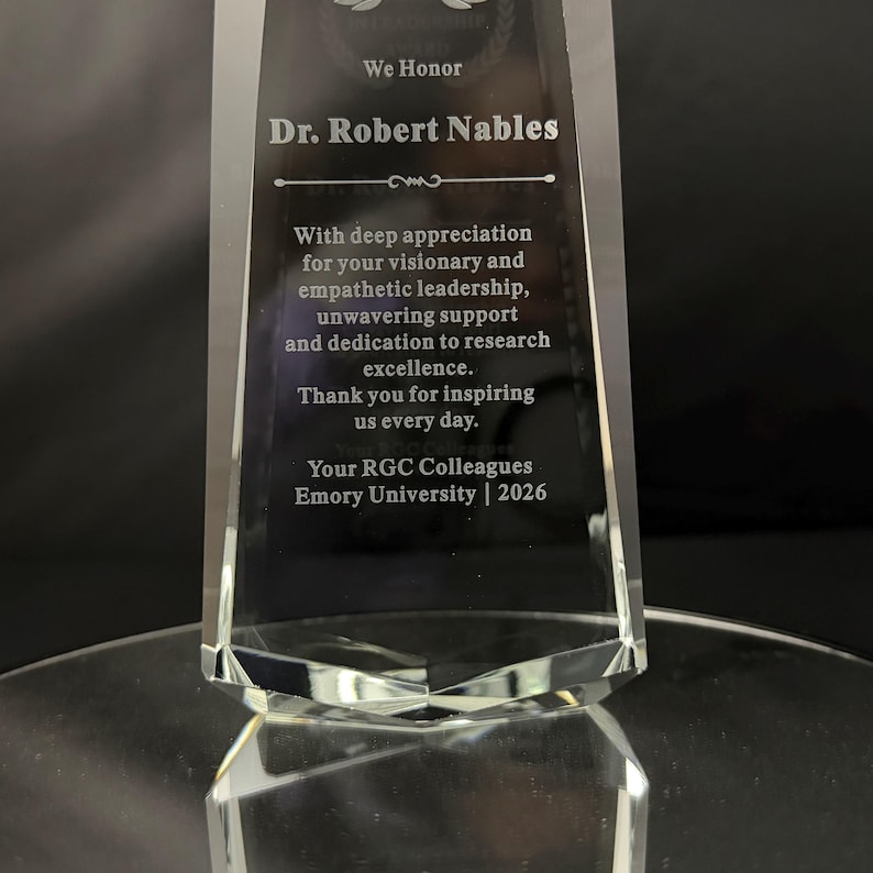 May include: A clear, tapered glass award trophy featuring an etched inscription that reads: We Honor Dr. Robert Nables. With deep appreciation for your visionary and empathetic leadership, unwavering support and dedication to research excellence.