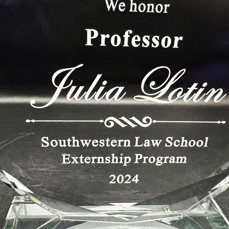 Puede incluir: Un premio de cristal transparente con el texto "We honor Professor Julia Lotin" en letras blancas. El premio tambi&eacute;n incluye "Southwestern Law School Externship Program 2024". La base del premio tiene un dise&ntilde;o geom&eacute;trico.
