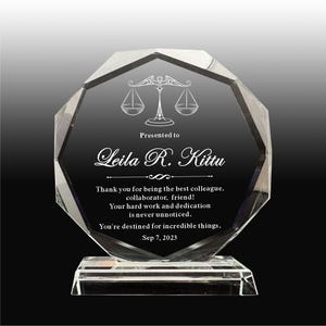Puede incluir: Un premio de vidrio transparente y facetado con una base negra. El premio presenta un icono de balanza grabado y el texto "Presented to Leila R. Kittu" y un mensaje de agradecimiento. También se incluye la fecha "Sep 7, 2023".