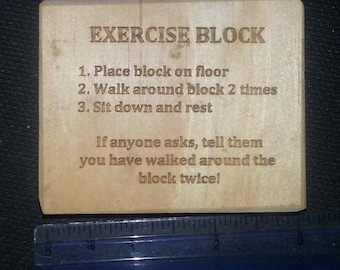 May include: A wooden block with instructions for an exercise routine. The instructions read: "EXERCISE BLOCK 1. Place block on floor 2. Walk around block 2 times 3. Sit down and rest If anyone asks, tell them you have walked around the block twice!"