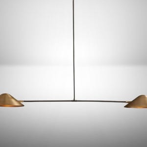 Może przedstawiać: Nowoczesna, minimalistyczna lampa wisząca. Posiada czarny, poziomy drążek z dwoma stożkowymi, złotymi kloszami. Światło zwisa z pojedynczego czarnego przewodu, tworząc elegancki, współczesny design.