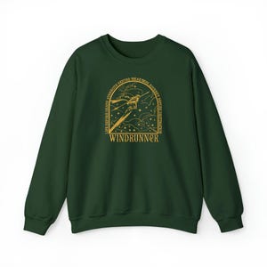 Puede incluir: Una sudadera verde oscuro con una ilustraci&oacute;n y texto dorados. El dise&ntilde;o incluye una figura estilizada con una espada, estrellas y la palabra "WINDRUNNER" debajo de un texto arqueado que dice "LIFE BEFORE DEATH, STRENGTH BEFORE WEAKNESS, JOURNEY BEFORE DESTINATION."