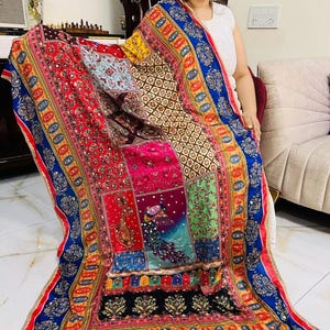May include: A colourful patchwork shawl with intricate embroidery and sequins. The shawl features a peacock design and a blue, yellow and red border.