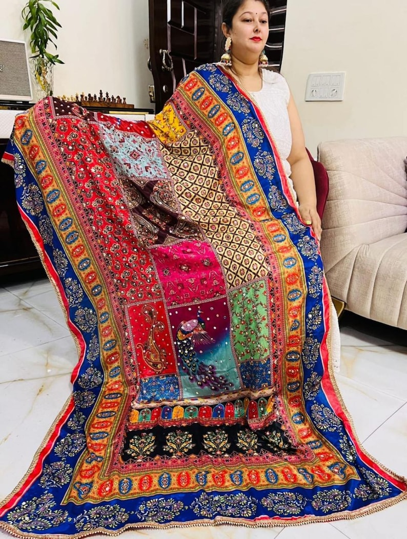 May include: A colourful patchwork shawl with intricate embroidery and sequins. The shawl features a peacock design and a blue, yellow and red border.