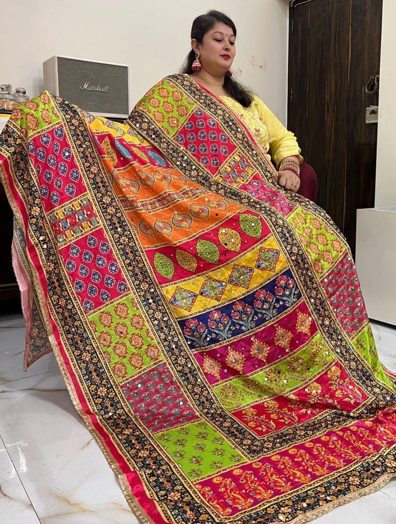 May include: A colourful patchwork dupatta with intricate embroidery and mirror work. The dupatta is made of a soft, flowing fabric and features a variety of colours, including red, pink, green, yellow, and blue.