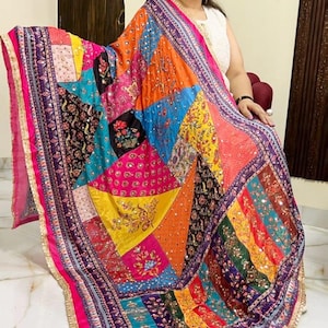 May include: A colourful patchwork shawl with intricate embroidery and sequins. The shawl is made of a variety of fabrics and features a geometric pattern. The shawl is trimmed with a gold border.