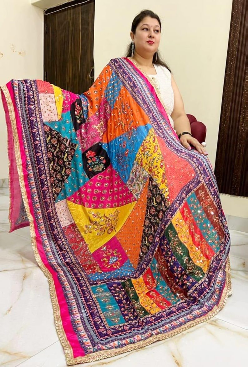 May include: A colourful patchwork shawl with intricate embroidery and sequins. The shawl is made of a variety of fabrics and features a geometric pattern. The shawl is trimmed with a gold border.