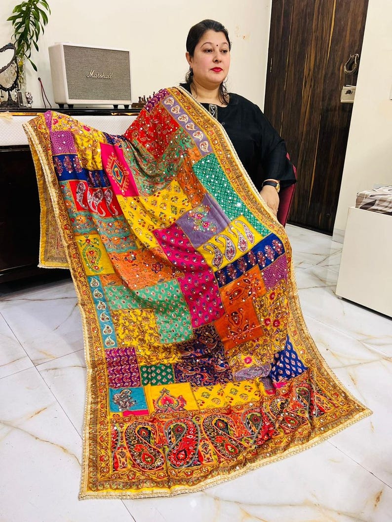 May include: A colourful patchwork shawl with gold embroidery and sequins. The shawl is made of a soft, flowing fabric and has a fringed edge.