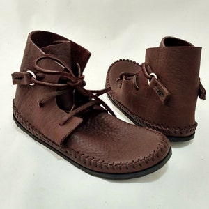 May include: A pair of brown leather ankle boots with laces and a decorative stitch around the sole.