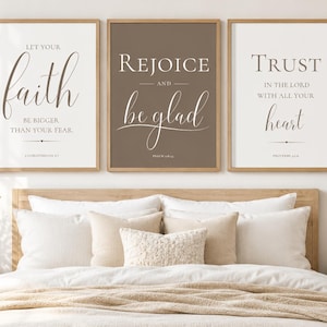 May include: Three rectangular wall art prints in light wood frames. The left print features white text on a cream background reading Let your faith be bigger than your fear. The center print has white text on a brown background reading Rejoice and be glad. The right print has dark text on a cream background reading Trust in the Lord with all your heart.