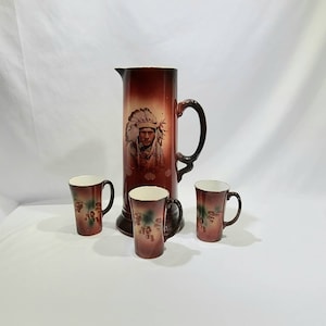 Pode incluir: Um conjunto de quatro canecas de cerâmica marrom com um design nativo americano. O jarro apresenta um retrato de um homem nativo americano com uma cobertura de cabeça. As canecas têm um design floral com bagas.