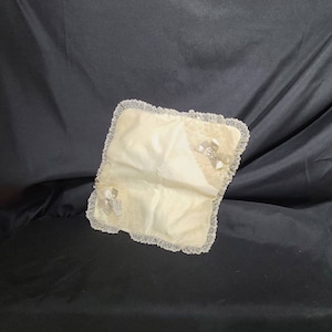 May include: A white satin pillow with lace trim and two satin bows. The pillow is perfect for a wedding ceremony or other special event.