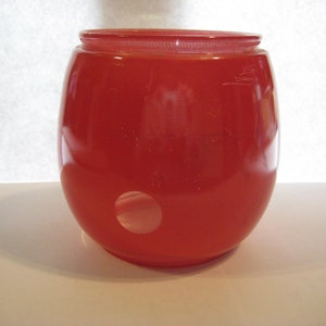 Puede incluir: Una pantalla de lámpara de vidrio roja de forma redonda con un agujero en la parte inferior.