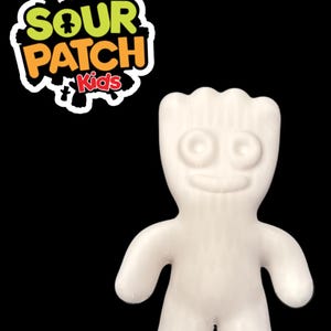 May include: White Sour Patch Kids gummy candy character. The character is shaped like a person with a big smile and two eyes.