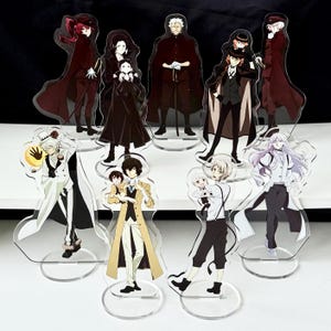 Peut inclure: Ensemble de figurines acryliques représentant des personnages d'anime. Les figurines présentent des personnages dans des tenues détaillées, avec diverses poses et expressions. Chaque figurine est montée sur une base circulaire transparente.