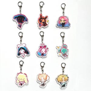 May include: Nine acrylic keychains with cartoon character designs. Each keychain features a silver keyring and a colorful, outlined illustration of a character. The characters have various hairstyles and outfits, with a white background.