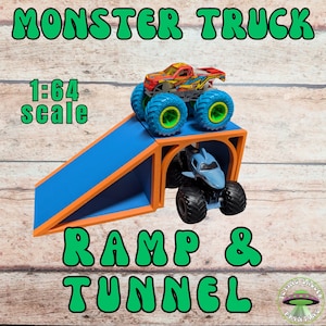 May include: A blue and orange ramp and tunnel set for toy monster trucks. The set includes two monster trucks, one red and yellow, and one blue. The text "MONSTER TRUCK", "1:64 scale", and "RAMP & TUNNEL" are displayed in green.
