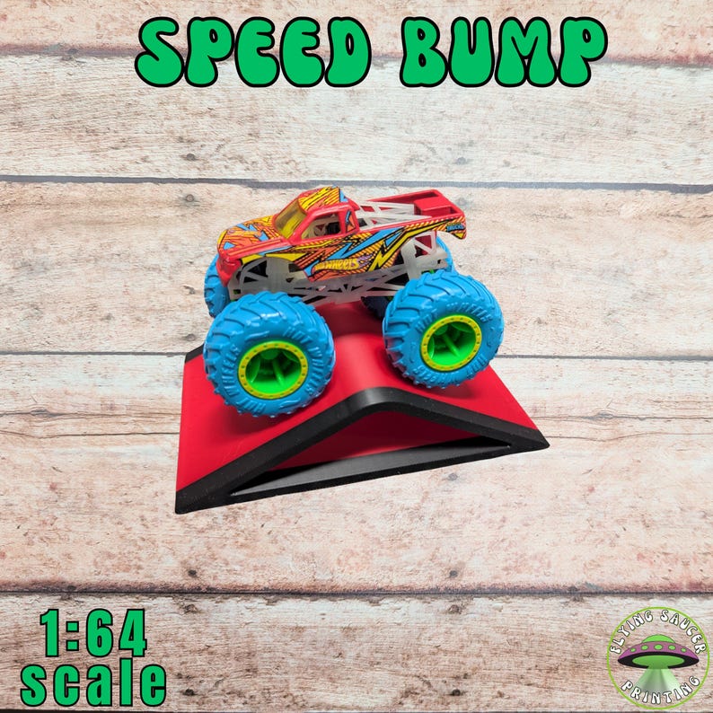 Peut inclure: Un dos d'&acirc;ne rouge avec une bordure noire soutient un jouet de camion monstre color&eacute; avec des pneus bleus et des jantes vertes. Le texte "SPEED BUMP" est au-dessus du camion, et "1:64 scale" est en dessous.