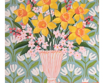 May include: A painting of a bouquet of yellow daffodils and pink flowers in a pink vase. The background features a light blue floral pattern with white flowers. The vase sits on a green surface.