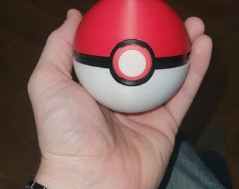 May include: A red and white Poké Ball, a spherical device used in the Pokémon franchise, is held in a hand. The ball has a red upper half, a white lower half, and a black band with a white button in the center. A wooden and metal watch is on the wrist.