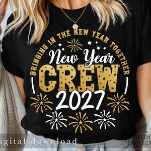 Könnte beinhalten: Ein schwarzes Kurzarm-T-Shirt mit einem gold-weißen Grafikdesign. Der Text "BRINGING IN THE NEW YEAR TOGETHER" steht in einem Kreis, mit "New Year CREW" und "2027" in der Mitte, umgeben von goldenen und weißen Feuerwerksdarstellungen.