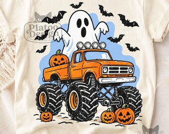 Puede incluir: Una camiseta de color crema con un gráfico de un camión monstruo naranja con neumáticos negros grandes. Un fantasma blanco está sentado en la parte trasera del camión y varios murciélagos negros vuelan al fondo. Tres calabazas están cerca.