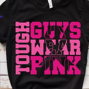 May include: Black t-shirt with the text "TOUGH GUYS WEAR PINK" in bright pink block letters. The shirt also has the logos for SVG, PNG, EPS, and DXF files. The shirt is made of a soft material.