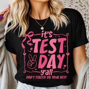May include: Black t-shirt with pink text that reads "it's TEST DAY -y'all- DON'T STRESS! DO YOUR BEST".