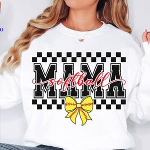 May include: White sweatshirt with black and white checkered pattern and the text "Mama Softball" in black with a red outline. A yellow and red softball bow is below the text.