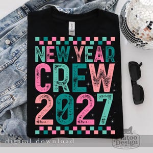 Pu&ograve; includere: Una t-shirt nera con il testo NEW YEAR CREW 2027 in un carattere testurizzato e usurato. Il design utilizza colori alternati verde acqua e rosa con piccoli accenti a forma di stella. Un bordo a scacchi incornicia la parte superiore e inferiore.