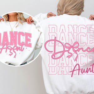 May include: White sweatshirt with the text "DANCE Aunt" in pink. The front of the sweatshirt has the words "DANCE Aunt" in a pink collegiate font. The back of the sweatshirt has the word "DANCE" repeated multiple times in a pink outline.