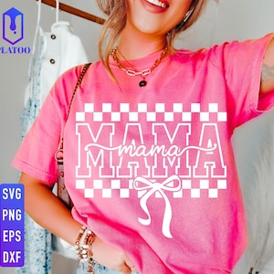 May include: A pink t-shirt with the word "MAMA" in a white, block letter design, with a cursive "mama" in the center. The design includes a checkered pattern and a bow. The shirt is a casual style.