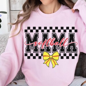 May include: Pink sweatshirt with a black and white checkered pattern and the text "Mama Softball" in black with a yellow and red softball bow.