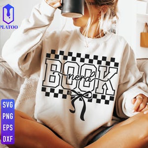 May include: Cream-colored sweatshirt with the word "BOOK" in a bold, black, checkered font, with "nerd" in cursive script. A black bow is below the text. The sweatshirt also has the text "SVG PNG EPS DXF" in a vertical column.