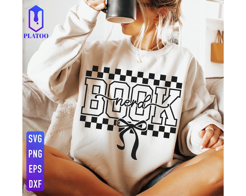 May include: Cream-colored sweatshirt with the word "BOOK" in a bold, black, checkered font, with "nerd" in cursive script. A black bow is below the text. The sweatshirt also has the text "SVG PNG EPS DXF" in a vertical column.
