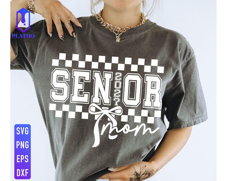 May include: Dark gray t-shirt with the words "SENIOR 2022 Mom" in white block letters and a bow graphic. The shirt has a checkered pattern above the text. The lower left corner has the text "SVG PNG EPS DXF".
