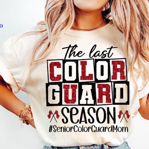 May include: Cream-colored t-shirt with the text "The last COLOR GUARD SEASON" in black and red. The shirt also includes the hashtag "#SeniorColorGuardMom" and a logo with SVG, PNG, EPS, and DXF text.