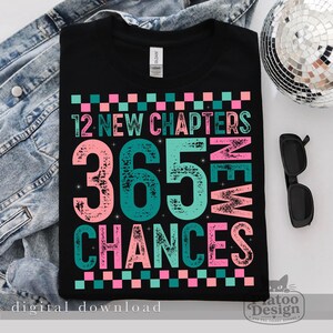 Pu&ograve; includere: Una t-shirt nera con un design grafico caratterizzato da un bordo a scacchi rosa e turchese. Il testo recita 12 NEW CHAPTERS 365 NEW CHANCES in un carattere multicolore dall'effetto usurato. Il design include piccoli accenti a stella.