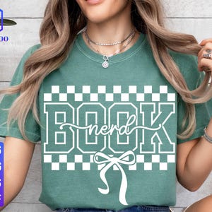 May include: A teal green t-shirt with the word "BOOK nerd" in white block letters and a bow graphic. The shirt has a checkered pattern above and below the text. The left side of the shirt has the text "SVG PNG EPS DXF".