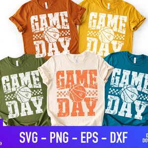 Puede incluir: Cinco camisetas en varios colores: naranja, amarillo, verde, crema y turquesa. Cada camiseta presenta el texto "GAME DAY" en una fuente blanca desgastada, con un gr&aacute;fico de baloncesto. La parte inferior de la imagen incluye el texto "SVG - PNG - EPS - DXF".