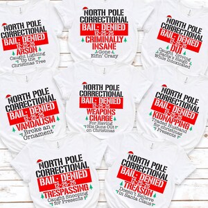 May include: White t-shirts with various humorous "North Pole Correctional Bail: Denied" designs. Each shirt features a red and black graphic with a Santa hat and a different Christmas-themed "crime" like "Arson" or "DUI".