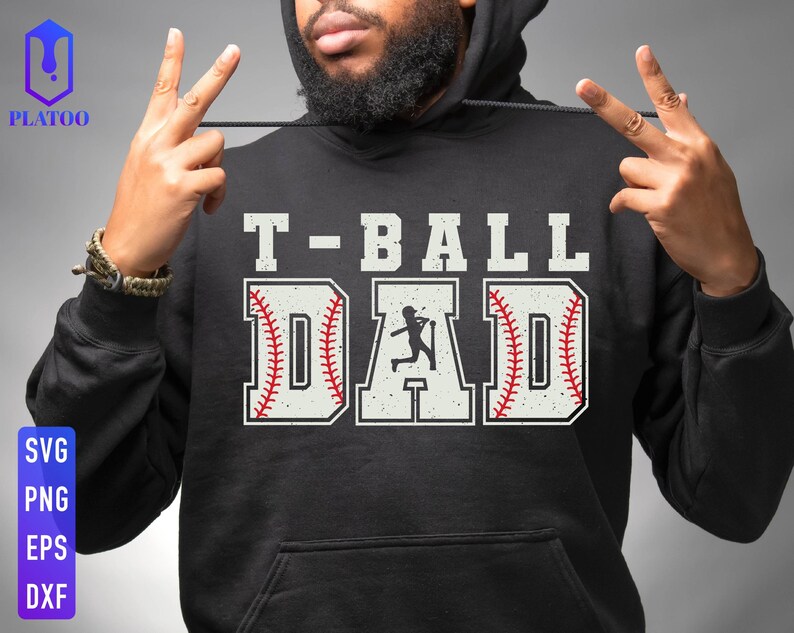 Puede incluir: Sudadera con capucha negra con el texto "T-BALL DAD" en letras blancas. La palabra "DAD" est&aacute; dise&ntilde;ada como una pelota de b&eacute;isbol con costuras rojas. Una silueta de un jugador de b&eacute;isbol est&aacute; en el centro de la palabra "DAD".