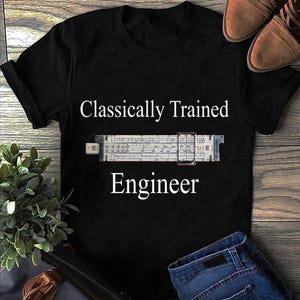 Könnte beinhalten: Ein schwarzes Kurzarm-T-Shirt mit dem weißen Text Classically Trained Engineer, der über und unter einer Grafik eines weißen Rechenschiebers mit einem transparenten Läufer zentriert ist. Das T-Shirt hat einen Rundhalsausschnitt.