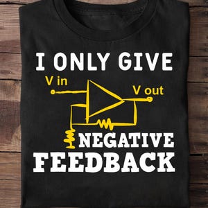 May include: Black t-shirt featuring the text "I ONLY GIVE NEGATIVE FEEDBACK" in white. A yellow electrical circuit diagram is printed below the text, with "V in" and "V out" labels.
