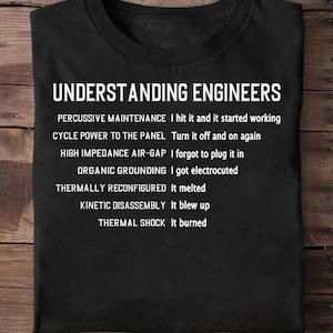 May include: Black t-shirt with the text "UNDERSTANDING ENGINEERS" in white. Below the title are engineering troubleshooting phrases and their outcomes, such as "Percussive Maintenance - I hit it and it started working."