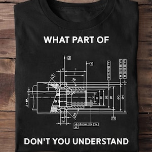 May include: A black short-sleeved t-shirt featuring a white technical engineering drawing of a mechanical component with various dimension lines and labels. The text WHAT PART OF is printed above the graphic and DON'T YOU UNDERSTAND below it.