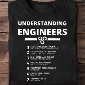 Peut inclure: T-shirt noir avec l'inscription blanche "UNDERSTANDING ENGINEERS". En dessous, sept étapes de dépannage d'ingénierie humoristiques, dont "Percussive Maintenance" et "Thermal Shock".
